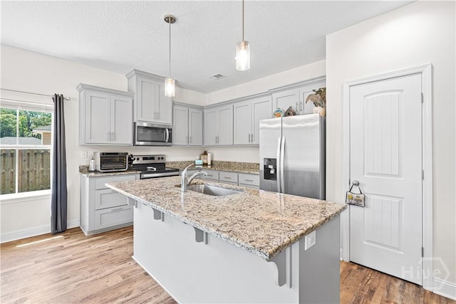208 Cherokee Oaks Xing, Hinesville, GA 31313 - kitchen with appliances with stainless steel finishes, a sink, gray cabinets, a kitchen bar, and light stone countertops