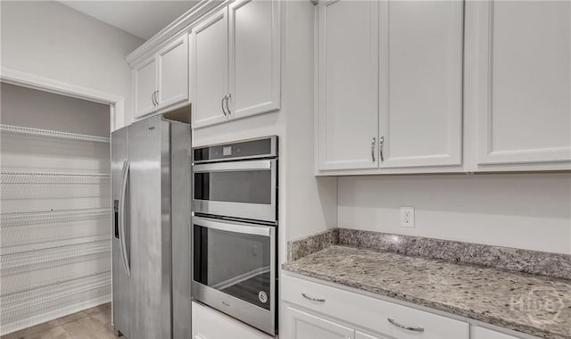 20 Lower Creek Dr, Richmond Hill, GA 31324 - kitchen featuring appliances with stainless steel finishes, white cabinets, light stone counters, and light wood-type flooring