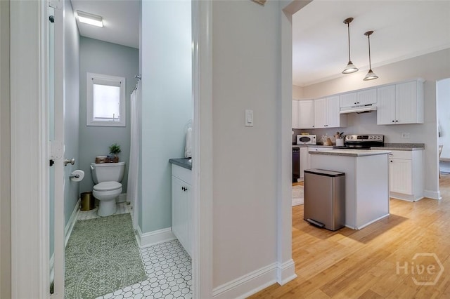 115 Daisy Ct, Savannah, GA 31404 - kitchen with stainless steel electric range, under cabinet range hood, white microwave, white cabinetry, and hanging light fixtures
