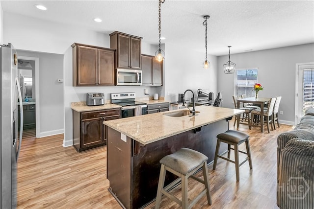 402 Abode Ave, Hinesville, GA 31313 - kitchen with appliances with stainless steel finishes, a sink, a breakfast bar, light wood-style floors, and dark brown cabinets