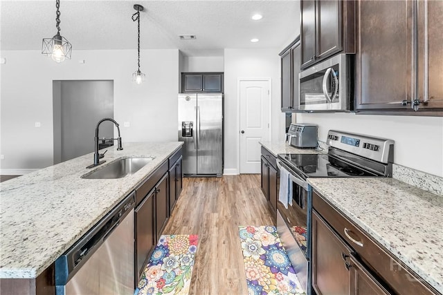 402 Abode Ave, Hinesville, GA 31313 - kitchen with stainless steel appliances, a sink, dark brown cabinets, light wood-style flooring, and light stone countertops