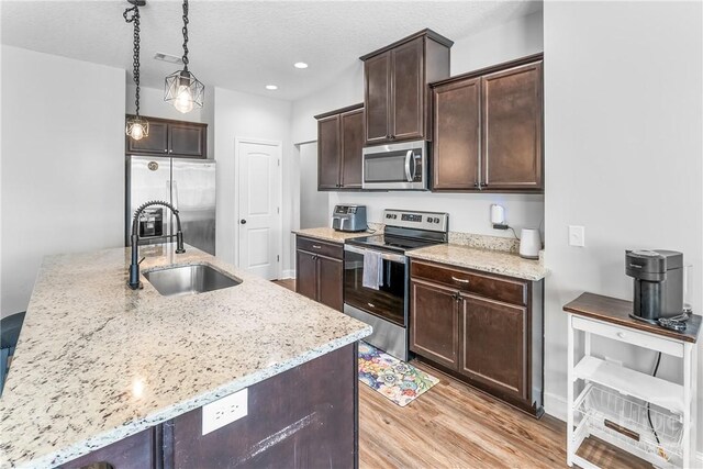 402 Abode Ave, Hinesville, GA 31313 - kitchen with appliances with stainless steel finishes, a sink, dark brown cabinetry, light wood finished floors, and light stone counters