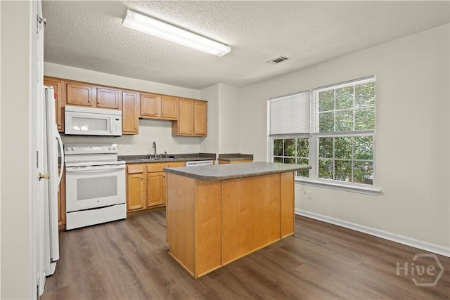 303 Aspen, Rincon, GA 31326 - kitchen featuring white appliances, a textured ceiling, a center island, dark wood-type flooring, and a sink