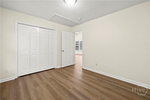 303 Aspen, Rincon, GA 31326 - unfurnished bedroom featuring attic access, wood finished floors, baseboards, a textured ceiling, and a closet