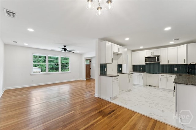 2310 Toussaint Ave, Savannah, GA 31404 - kitchen with stainless steel microwave, a sink, light wood-type flooring, tasteful backsplash, and baseboards