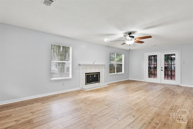 17 Walthour Cv, Savannah, GA 31410 - unfurnished living room featuring a ceiling fan, a tile fireplace, light wood-style flooring, baseboards, and french doors