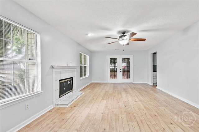 17 Walthour Cv, Savannah, GA 31410 - unfurnished living room featuring ceiling fan, a tile fireplace, light wood finished floors, french doors, and baseboards