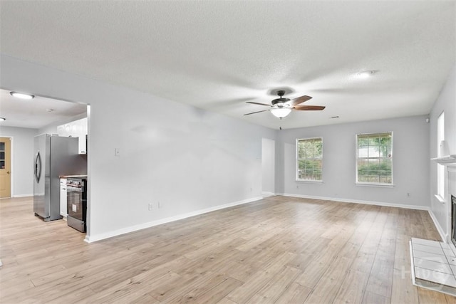 17 Walthour Cv, Savannah, GA 31410 - unfurnished living room with a fireplace, ceiling fan, light wood-type flooring, a textured ceiling, and baseboards