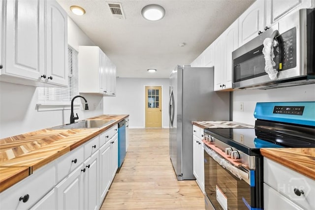 17 Walthour Cv, Savannah, GA 31410 - kitchen with appliances with stainless steel finishes, wooden counters, light wood finished floors, a sink, and white cabinets