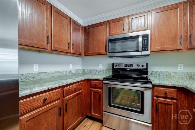 428 Roberts Way, Rincon, GA 31326 - kitchen with stainless steel appliances, ornamental molding, brown cabinets, light wood-style flooring, and light stone countertops