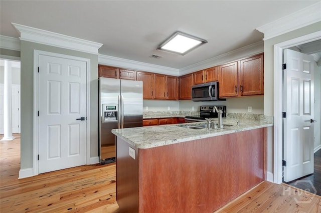 428 Roberts Way, Rincon, GA 31326 - kitchen with appliances with stainless steel finishes, a peninsula, brown cabinetry, light wood-style floors, and a sink