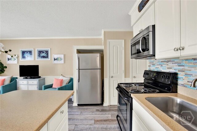 1217 Bay St Unit 105B, Tybee Island, GA 31328 - kitchen featuring appliances with stainless steel finishes, crown molding, a textured ceiling, light wood-style floors, and tasteful backsplash
