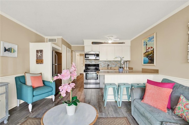 1217 Bay St Unit 105B, Tybee Island, GA 31328 - living area with dark wood-style flooring, a wainscoted wall, a ceiling fan, and crown molding