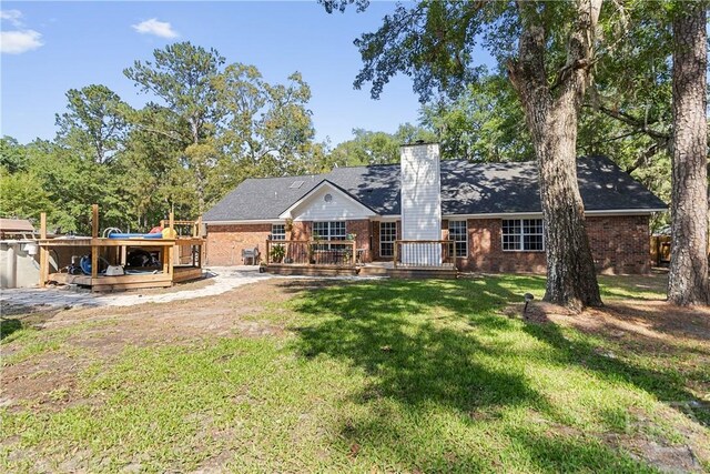 67 Oak Side Ct, Richmond Hill, GA 31324 - rear view of house featuring a chimney, a deck, brick siding, and a lawn
