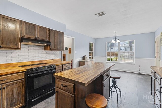 67 Oak Side Ct, Richmond Hill, GA 31324 - kitchen featuring butcher block countertops, under cabinet range hood, black electric range oven, wainscoting, and a kitchen bar