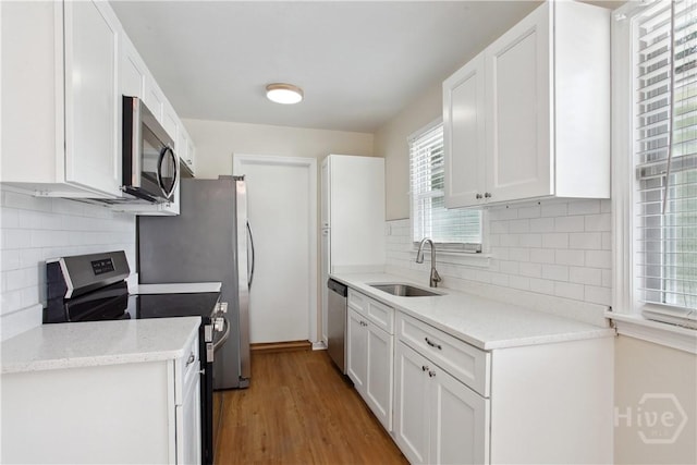 2301 Pinetree Rd, Savannah, GA 31404 - kitchen with stainless steel appliances, a sink, white cabinets, light wood-style flooring, and tasteful backsplash