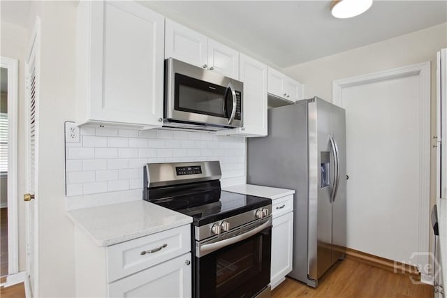 2301 Pinetree Rd, Savannah, GA 31404 - kitchen with appliances with stainless steel finishes, light wood-type flooring, tasteful backsplash, and white cabinetry