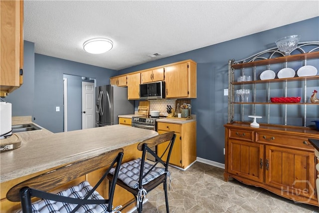 267 Jasper Ln, Rincon, GA 31326 - kitchen featuring appliances with stainless steel finishes, light countertops, tasteful backsplash, a textured ceiling, and a peninsula