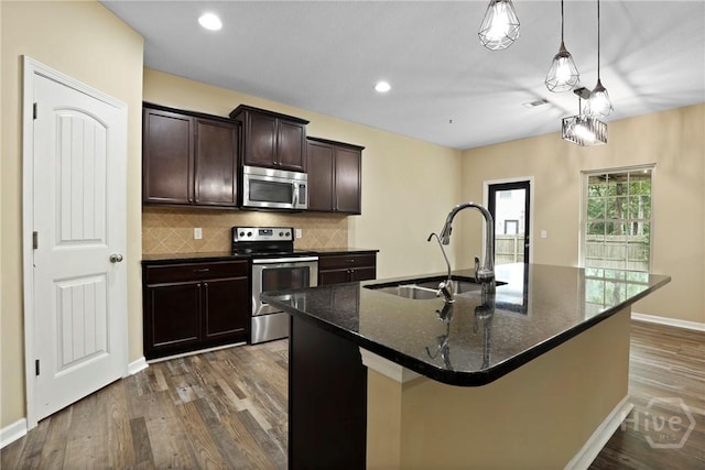 93 Veranda Trl, Midway, GA 31320 - kitchen with appliances with stainless steel finishes, a sink, dark wood-type flooring, decorative backsplash, and a center island with sink