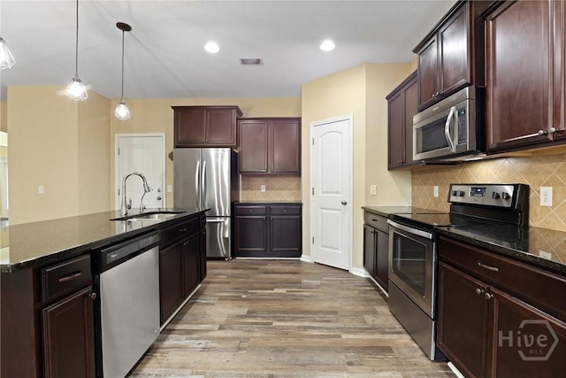 93 Veranda Trl, Midway, GA 31320 - kitchen featuring stainless steel appliances, a sink, decorative backsplash, light wood finished floors, and dark stone countertops