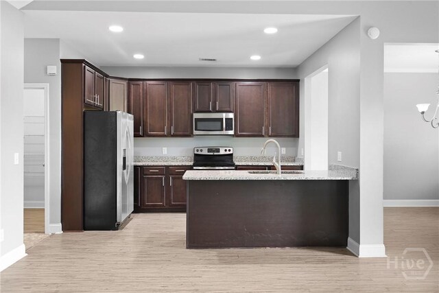 7 Sailmaker Ln, Richmond Hill, GA 31324 - kitchen with appliances with stainless steel finishes, a sink, dark brown cabinets, light wood-style floors, and recessed lighting