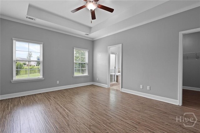 7 Sailmaker Ln, Richmond Hill, GA 31324 - unfurnished bedroom with a tray ceiling, a spacious closet, dark wood finished floors, a closet, and baseboards