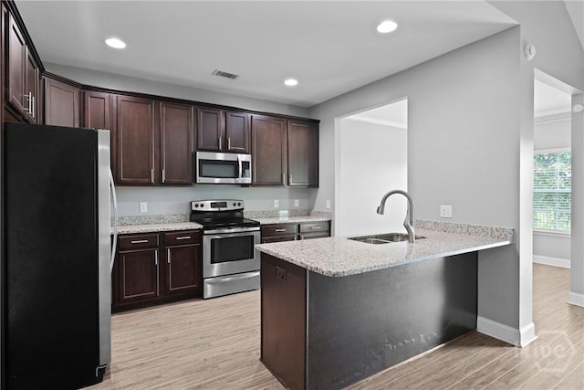 7 Sailmaker Ln, Richmond Hill, GA 31324 - kitchen with appliances with stainless steel finishes, a sink, dark brown cabinetry, light wood-style flooring, and a peninsula