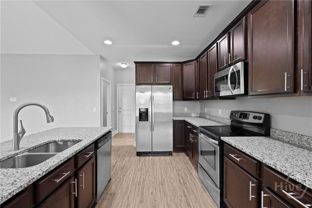 7 Sailmaker Ln, Richmond Hill, GA 31324 - kitchen with appliances with stainless steel finishes, a sink, light stone counters, dark brown cabinets, and recessed lighting