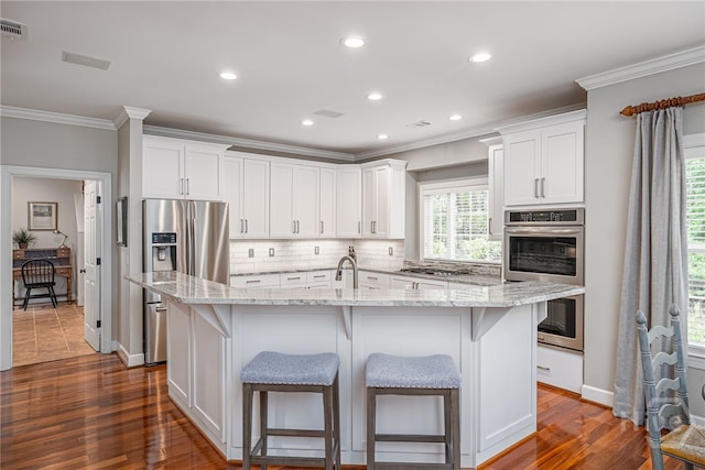 14 Black Hawk Trl, Savannah, GA 31411 - kitchen with appliances with stainless steel finishes, ornamental molding, tasteful backsplash, a kitchen island with sink, and white cabinetry