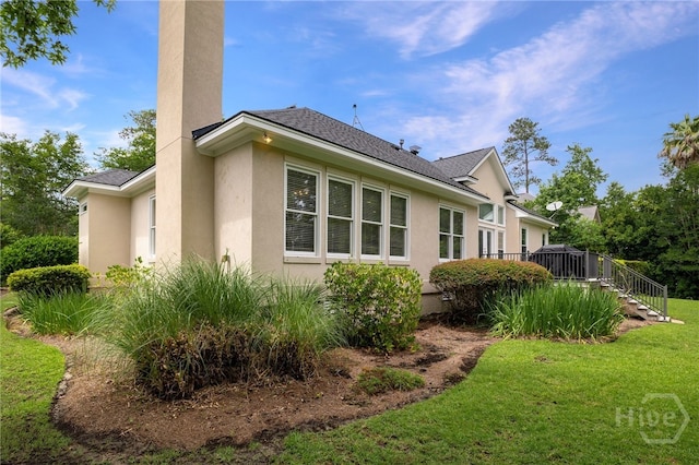 35 Wild Thistle Ln, Savannah, GA 31406 - view of home's exterior featuring stucco siding, a lawn, stairs, roof with shingles, and a wooden deck