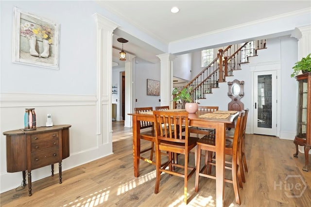 711 Chastain Cir, Richmond Hill, GA 31324 - dining room with ornate columns, light wood-style floors, crown molding, and stairs