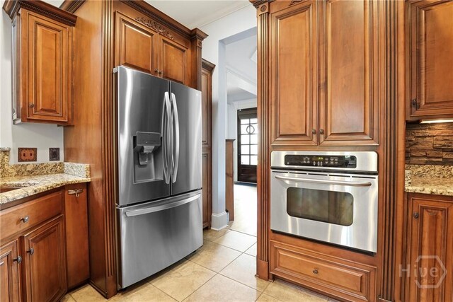 711 Chastain Cir, Richmond Hill, GA 31324 - kitchen with stainless steel appliances, light stone countertops, brown cabinets, light tile patterned floors, and crown molding