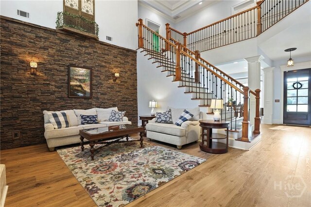 711 Chastain Cir, Richmond Hill, GA 31324 - living room with a towering ceiling, wood finished floors, ornate columns, stairs, and crown molding
