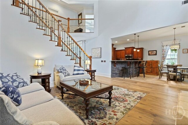 711 Chastain Cir, Richmond Hill, GA 31324 - living area featuring light wood finished floors, stairs, crown molding, a high ceiling, and baseboards