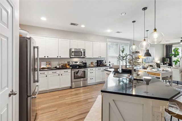 131 Tanzania Trl, Pooler, GA 31322 - kitchen with stainless steel appliances, a sink, light wood-style floors, white cabinets, and open floor plan