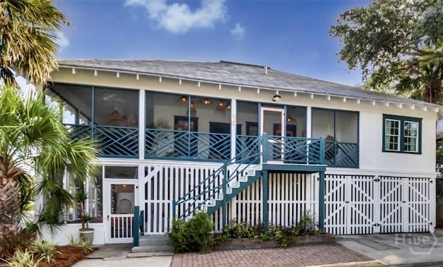 16 12th St, Tybee Island, GA 31328 - view of front facade featuring stairway, a sunroom, and roof with shingles