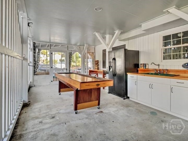 16 12th St, Tybee Island, GA 31328 - kitchen with black refrigerator with ice dispenser, a sink, concrete flooring, white cabinets, and butcher block counters