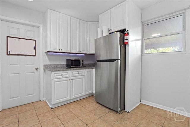 2030 E 42nd St, Savannah, GA 31404 - kitchen featuring appliances with stainless steel finishes, white cabinets, light tile patterned floors, baseboards, and light stone countertops
