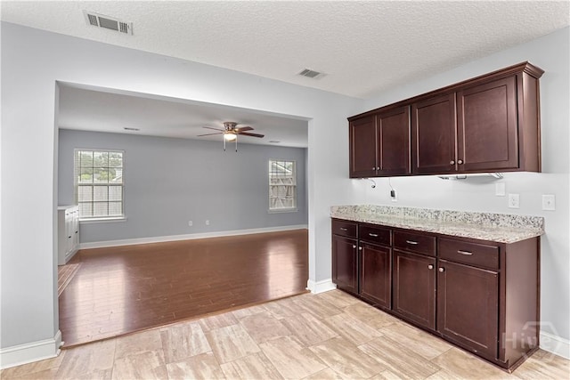 42 Kinlock Ct, Midway, GA 31320 - kitchen featuring ceiling fan, light stone countertops, baseboards, a textured ceiling, and dark brown cabinetry