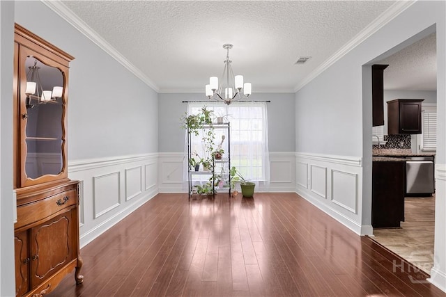 42 Kinlock Ct, Midway, GA 31320 - dining room with a chandelier, a textured ceiling, wainscoting, wood finished floors, and a decorative wall