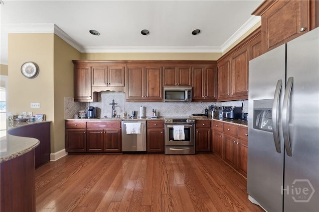 745 S Chickasaw Trl, Sparta, GA 31087 - kitchen with appliances with stainless steel finishes, crown molding, dark wood-type flooring, decorative backsplash, and light stone countertops