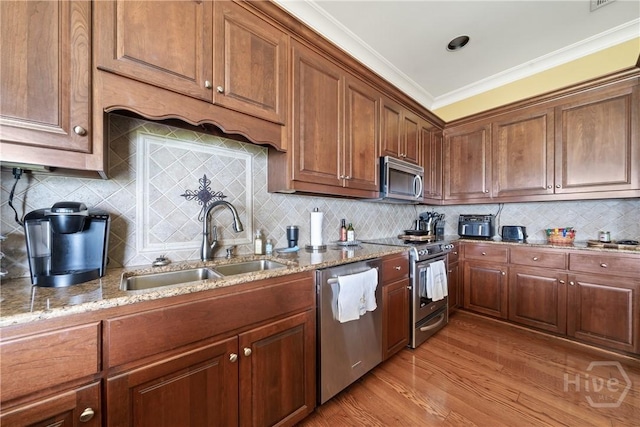 745 S Chickasaw Trl, Sparta, GA 31087 - kitchen featuring appliances with stainless steel finishes, a sink, light stone counters, light wood-type flooring, and crown molding