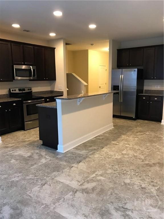 60 Kepler Loop, Richmond Hill, GA 31324 - kitchen with stainless steel appliances, recessed lighting, baseboards, an island with sink, and dark stone counters