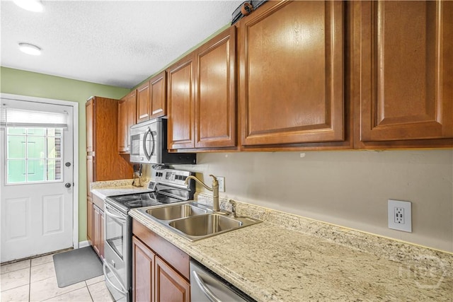 727 S Main St Unit 117, Hinesville, GA 31313 - kitchen with appliances with stainless steel finishes, a sink, brown cabinets, a textured ceiling, and light tile patterned floors