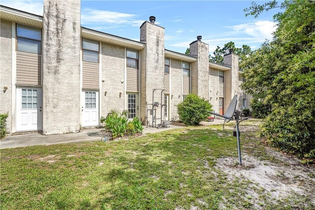 727 S Main St Unit 117, Hinesville, GA 31313 - rear view of house featuring a yard, stucco siding, and a chimney