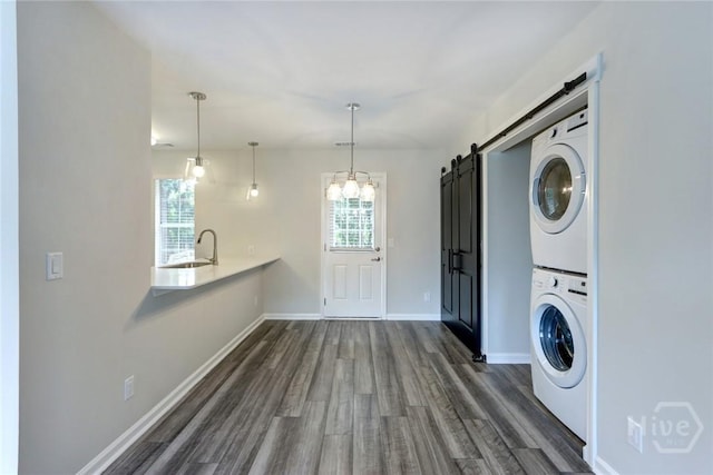 106 Oyster Catcher Ln, Savannah, GA 31410 - laundry room with estacked washer and dryer, a barn door, dark wood finished floors, and baseboards