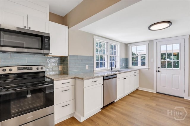 55 Saint Johns Ave, Savannah, GA 31404 - kitchen featuring appliances with stainless steel finishes, a sink, light wood-style flooring, light stone counters, and white cabinets