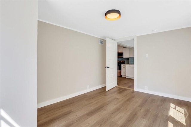 55 Saint Johns Ave, Savannah, GA 31404 - empty room featuring light wood-style flooring, baseboards, and ornamental molding
