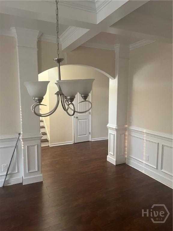 153 Spoonbill Cir, Savannah, GA 31405 - unfurnished dining area featuring dark wood-type flooring, crown molding, a wainscoted wall, arched walkways, and a decorative wall