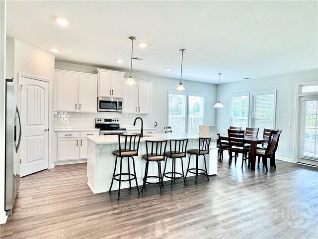 128 Melody Dr, Pooler, GA 31322 - kitchen featuring stainless steel appliances, a center island with sink, wood finished floors, light countertops, and recessed lighting